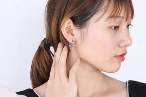 Close-up of a woman wearing silver steel bead hoop earrings with a metallic finish