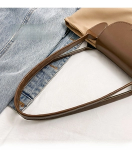 Detail of wide brown leather handles and neat stitching on a nylon tote bag