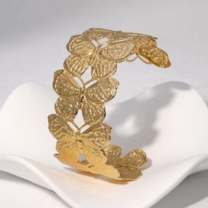Polished 18k gold butterfly open bangle with intricate cutout design on wave pedestal