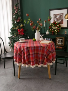 Detail of red plaid round tablecloth with white tassels in a festive Christmas dining room