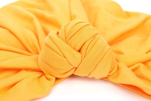 Detailed close-up of a soft knitted turban featuring a stylish knotted design in orange