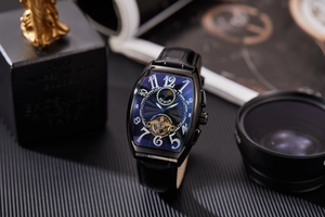Detail of tonneau-shaped mechanical watch with blue skeleton dial and black leather strap