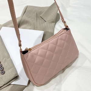 Sac sous le bras rose matelassé avec surpiqûres en losange sur un blazer gris chic