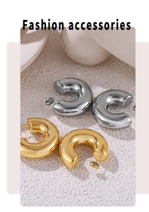 Macro detail of polished C-shaped hoop earrings in gold and silver finish on white sand