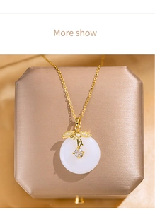 Detailed macro view of a gold-plated necklace with white jade pendant and zircon inlay
