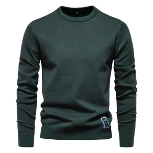 Détail du col rond côtelé et de la texture en maille de coton d'un pull-over vert foncé