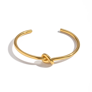 Detailaufnahme einer minimalistischen goldenen Knotenspange mit polierter Spiegeloberfläche