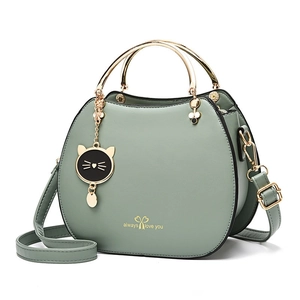 Light green shell crossbody bag with metal ring handles and cat-shaped pendant detail