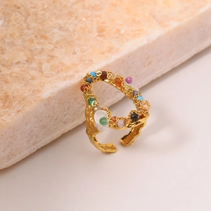 Gold open titanium steel ring with colorful beads on a natural stone textured background