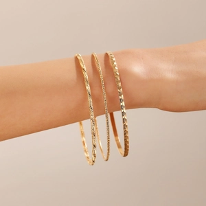 Three-piece gold bangle set with hammered and textured finish for a minimalist chic look