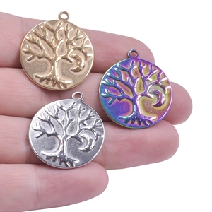 Detailed view of three small stainless steel tree of life charms held on fingertips