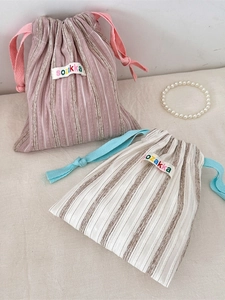 Vertical striped drawstring storage bags in pink and beige colors for travel organization