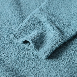 Detailed close-up of blue chenille knit fabric texture and ribbed cuff on men's sweater