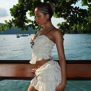 Detail of white pleated chiffon two-piece set featuring black straps and a mini skirt
