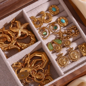 Macro shot of 18K gold plated earrings with hammered texture and turquoise in a jewelry box