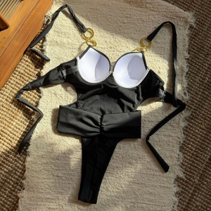 Detail of black cutout swimsuit showing gold ring accents and white padded cups