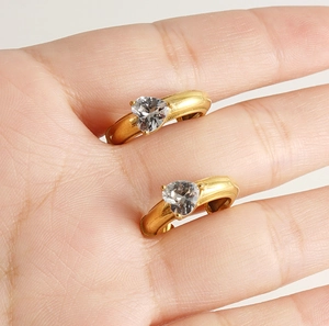 Detail showing heart-shaped zircon charms on 18k gold-plated C-shaped hoop earrings