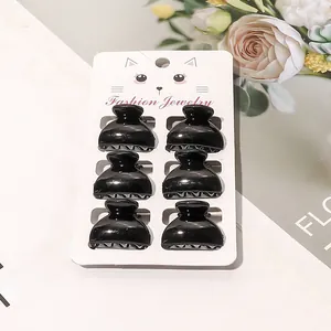 Detailed view of six black mini plastic hair claws on a fashion jewelry display card