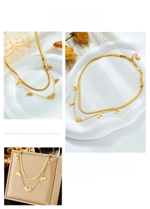 Detail of layered gold titanium necklace featuring a snake chain and heart charms
