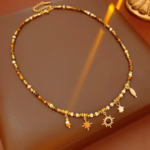 Detail of beaded ethnic necklace with golden sun and star charms on leather base