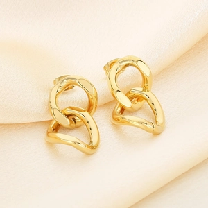 Macro view of gold interlocking geometric earrings on elegant pleated white silk fabric