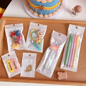 Flat lay of macaron color stationery and jewelry sets in individual zip bags on wooden tray