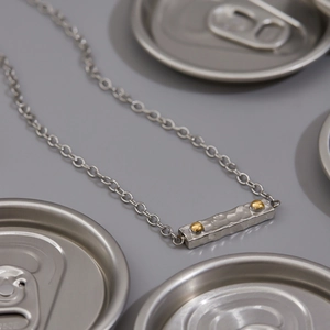 Detailed view of bicolor 18K gold and stainless steel can tab pendant necklace with texture