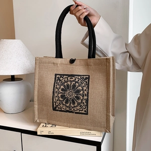 Large khaki linen tote bag with black floral print shown by a model in a home setting