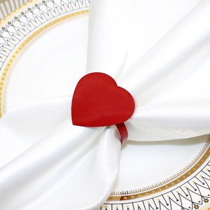 Close-up of a red heart-shaped metal napkin ring with shiny finish on white cloth