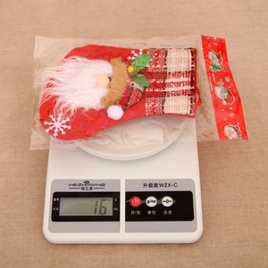 Detailed view of a red velvet Christmas stocking being weighed at 16 grams on a scale