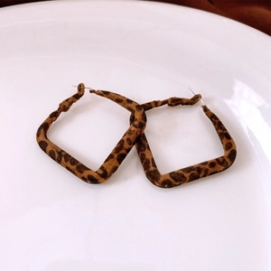 Detailed close-up of square leopard print earrings with a soft flocked velvet texture