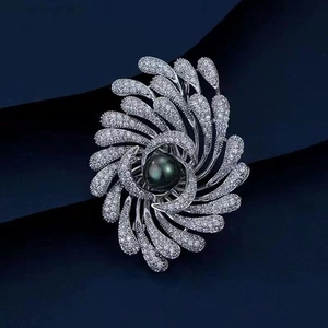 Luxury feather brooch with silver metal, crystal pavé and black pearl on dark background