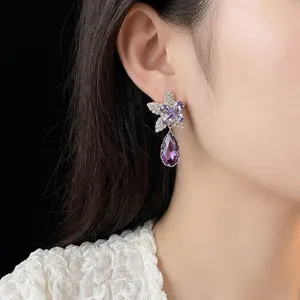 Boucles d'oreilles fleur violette élégantes avec cristaux et pierres portées par un modèle
