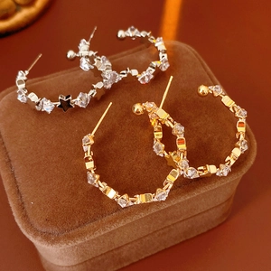 Detail of silver and gold C-shaped star earrings with sparkling cubic zirconia inlay