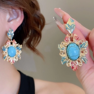 Detail of vintage turquoise stud earrings with decorative gold frames and leaf accents