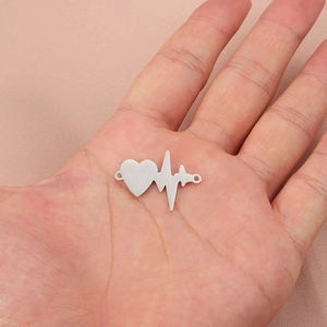 Polished silver heart heartbeat pendant connector on palm with pink background
