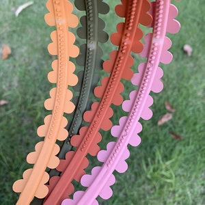 Detail of four matte candy-colored non-slip floral headbands on green grass