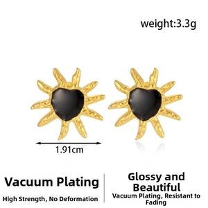 Close-up of golden sunburst heart earrings with black enamel and hammered metal finish
