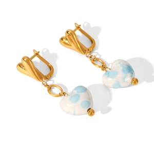 Détail de boucles d'oreilles dorées avec cœur blanc moucheté bleu et pendentifs ronds