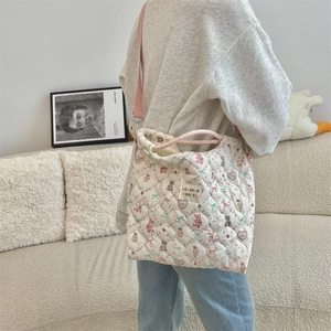 Quilted tote bag with cute cartoon prints and pink adjustable strap worn by a model