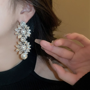 Elegant floral drop earrings with faux pearls and rhinestones on a female model