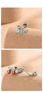 Macro detail of cherry stud earrings with bow and red or blue zircon screw backs