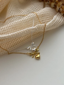 Detailed view of elegant bow and heart pendants on gold and silver necklaces