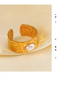 Detail of wide hammered gold ring with pearl inlay on soft silk background