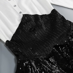 Détail de blazer noir et blanc avec broderie de paillettes et boutons strass