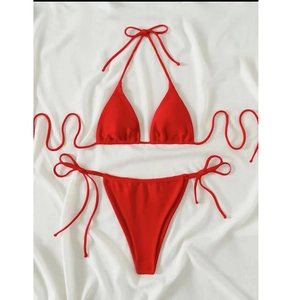 Close-up of red triangle bikini set with adjustable side ties on white fabric backdrop