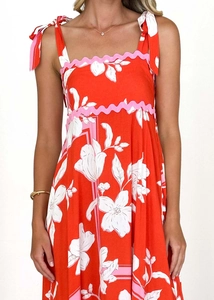 Close-up of red floral A-line dress featuring pink scalloped trim and bow tie straps