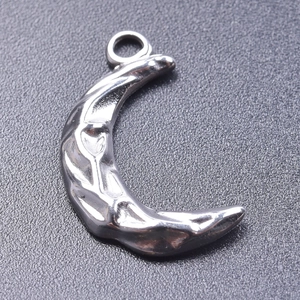 Detail view of crescent moon pendant with hammered metal texture and silver finish
