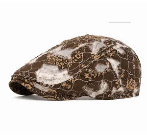Macro detail of floral embroidery and distressed mesh texture on brown beret hat