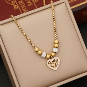 Golden heart tree of life necklace with crystals in a beige jewelry box on books